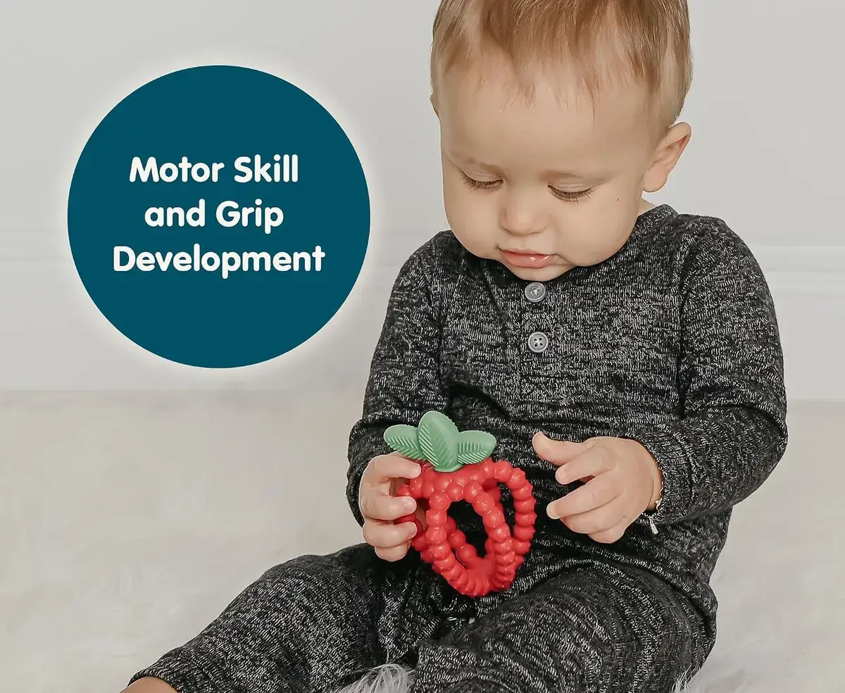 baby holding a strawberry silicone teething toy