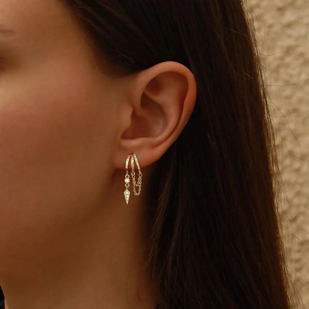 gold dangle huggie earrings on a model